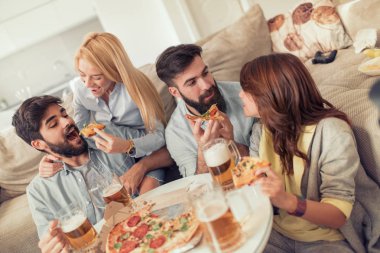 Pizza yiyip evde bira içmeyi gülümseyen arkadaşlar