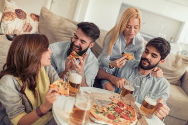Pizza yiyip evde bira içmeyi gülümseyen arkadaşlar