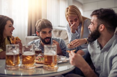 Pizza yiyip evde bira içmeyi gülümseyen arkadaşlar