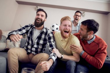 Grup arkadaşıyla futbol maçı televizyonda izlerken gol birlikte kutluyor.