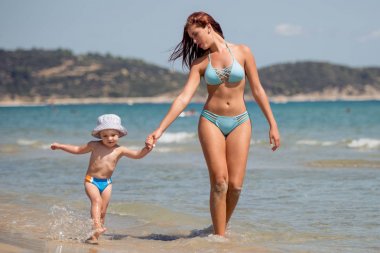 Küçük bir çocuk ile bir yürüyüş deniz kenarına olan kadın.