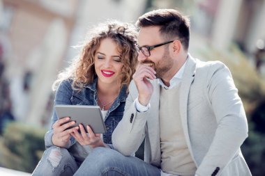 Açık havada eğleniyor ve gülümseyerek, tablet üzerinde seyir mutlu genç Çift.
