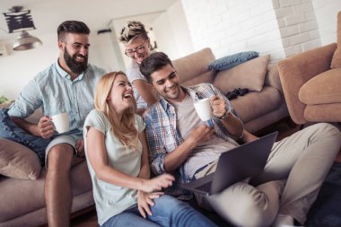 Birlikte kanepede oturan ve laptop komik video izlerken arkadaşlar.