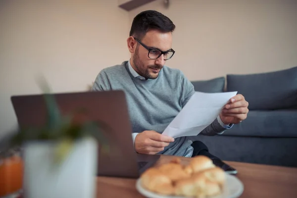 Young man running small business from home office, working on laptop.