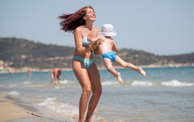 Küçük bir çocuk ile bir yürüyüş deniz kenarına olan kadın.