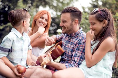 Mutlu aile eğleniyor park, gitar çalmak.