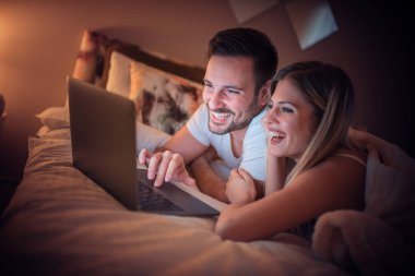 Birlikte laptop ile kendi yatak odasında rahatlatıcı romantik genç Çift