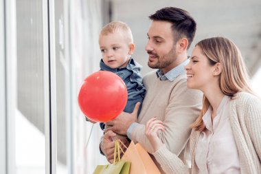 Satılık, tüketim ve aile kavramı - alışveriş torbaları ile mutlu aile ve vitrin City bakarak onların oğlu,.