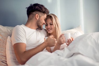 Seven çift yatakta genç sabah kahve içmek. Modern yaşam kavramı.