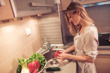 Mutfak, lavabo sebze yıkama kadın bir öğle yemeği hazırlamak.