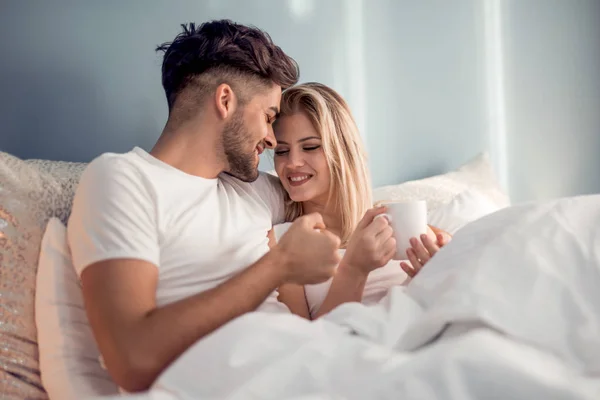 可爱的情侣在床上喝着早晨的咖啡 现代生活方式概念 — 图库照片