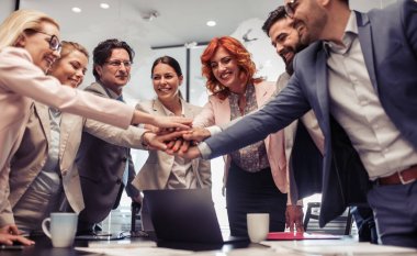 Modern ofis birlikte ellerini koyarak toplantıda başarılı iş arkadaşları