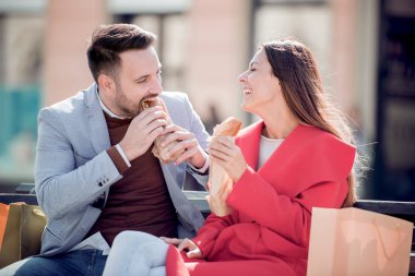 bankta oturan ve alışveriş sonra sandviç yeme bir çift 