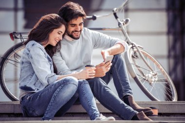 Mutlu genç çift akıllı telefondan selfie çekiyor.