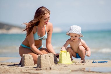 Anne ve oğlu tropik sahilde kum kaleler yapmak 