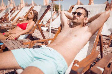 kaç koltuklarda oturan ve tatil sırasında kumsalda güneşlenme Mayo içinde  