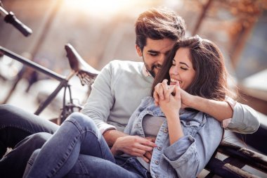 Mutlu genç çift Bisiklet arka plan üzerinde bankta oturmuş