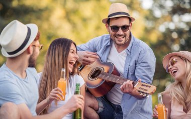 Piknik ve gitar parkta gündüz oynayan arkadaş grubu