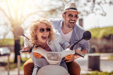 Mutlu genç çift scooter sürme sırasında dışarıda eğleniyor