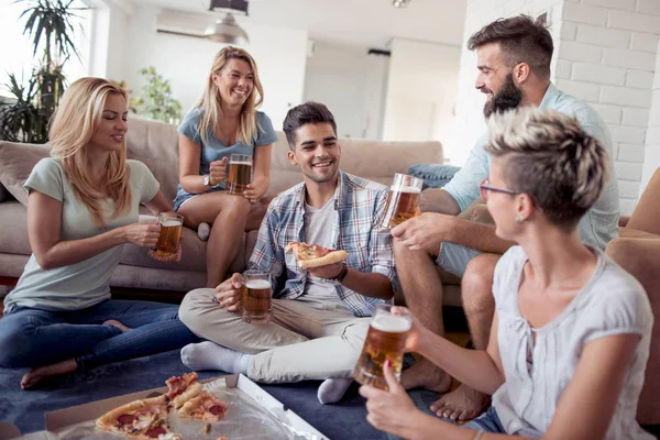 Group of young people eating pizza while having fun together