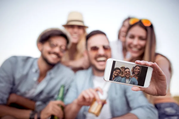group of friends taking selfie on smartphone outdoors during vacation