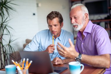 Modern ofiste dizüstü bilgisayarda çalışan iki işadamı..