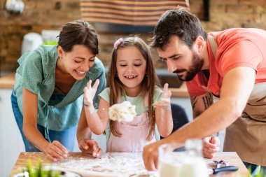 Mutfakta mutlu bir aile var. Anne, baba ve kız hamuru hazırlıyor..