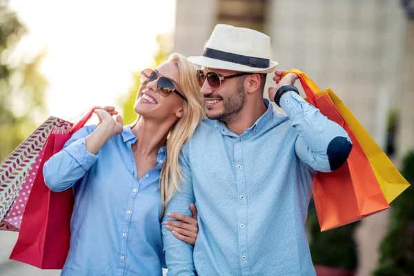 Portrait of handsome couple with shopping bags in the city.