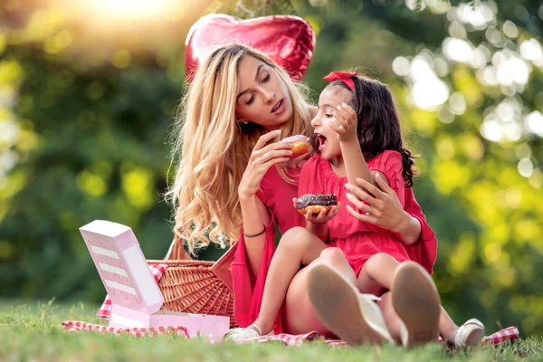 夏の公園でピクニックをしている家族魅力的なお母さんと彼女の娘は公園で楽しんでいます — ストック写真