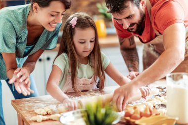 Mutfakta mutlu bir aile var. Anne, baba ve kız hamuru hazırlıyor..