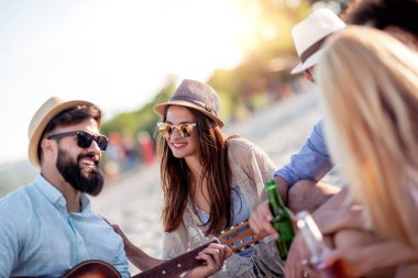 Bir grup arkadaş gitar çalıyor, eğleniyor ve gün batımında kumsalda parti yapıyorlar..