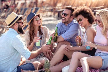 Mutlu genç insanlar iyi bir ruh hali içinde ve plajda piknik yapıyorlar. Yaşam tarzı, aşk, flört ve tatil konsepti.