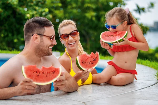 Feliz familia joven en la piscina en el día de verano — Foto de Stock