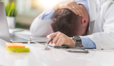 Hastanedeki pencerenin yanında oturan ve dizüstü bilgisayar kullanan bilinmeyen doktoru kapatın..