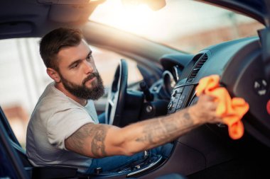 Arabasını bir bezle açık havada günbatımında temizlik genç bir adam portresi.