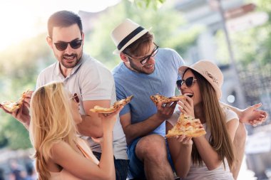 Oturup pizza yiyen, dışarıda eğlenen canavarlar. Randevu, tüketim, gıda ve yaşam tarzı konsepti.