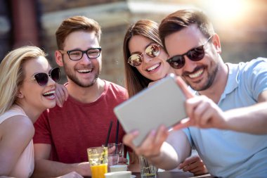 Neşeli bir grup arkadaş kafede eğleniyor, selfie çekiyor..