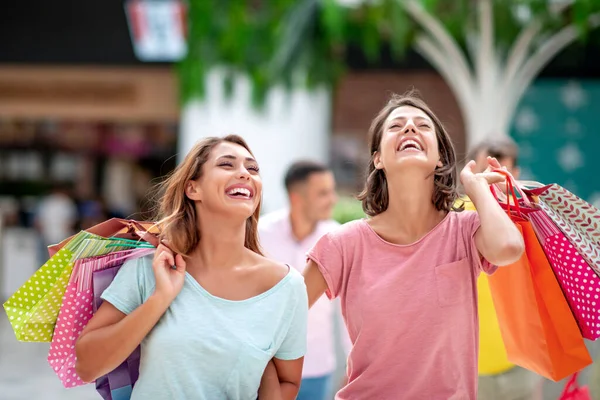 两个女性朋友带着购物袋在城里购物后很开心 — 图库照片