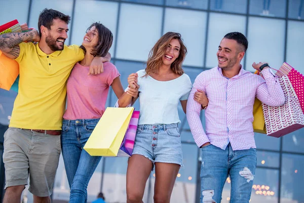 Şehirde alışveriş torbaları olan bir grup arkadaş. Alışveriş, turizm ve arkadaşlık kavramı..