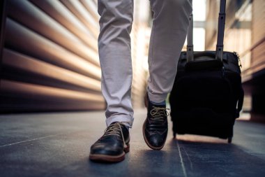 Bacaklarını kapat. Bavulları şehirde taşıyan adam. İş, yaşam tarzı ve seyahat konsepti..