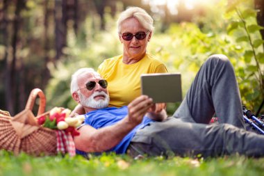 Üst düzey çift doğanın tadını çıkarıyor ve dijital tablet kullanıyorlar..
