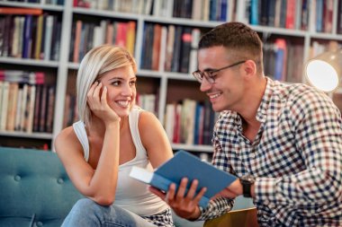 Birkaç öğrenci kütüphanede kitap okuyor. Eğitim, üniversite, halk ve yaşam tarzı kavramı.