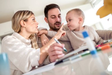 Anne ve baba evde çocuklarıyla birlikte resim çiziyorlar..
