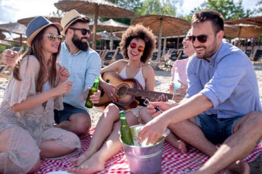 Bir grup çekici genç sahilde eğleniyor, içiyor ve kadeh kaldırıyor..