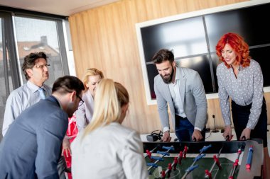 İş adamları birlikte harika vakit geçiriyorlar. Meslektaşlar modern ofiste masa futbolu oynuyorlar.. 