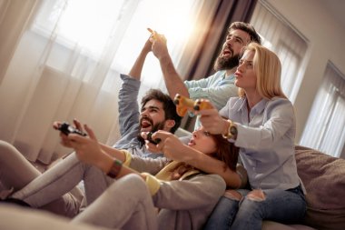 Modern bir dairede oturan ve video oyunları oynayan bir grup genç arkadaş. Arkadaşlık, teknoloji, oyunlar ve ev kavramı.