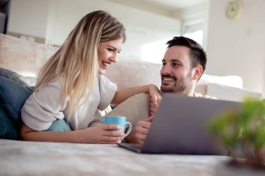 Evde dizüstü bilgisayarla çalışan genç bir çift..