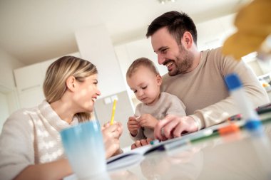 Anne ve baba evde çocuklarıyla birlikte resim çiziyorlar..
