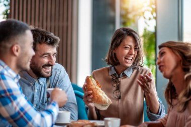 Alışveriş merkezindeki kafede kahvaltı yapan ve kahve içen dört genç..