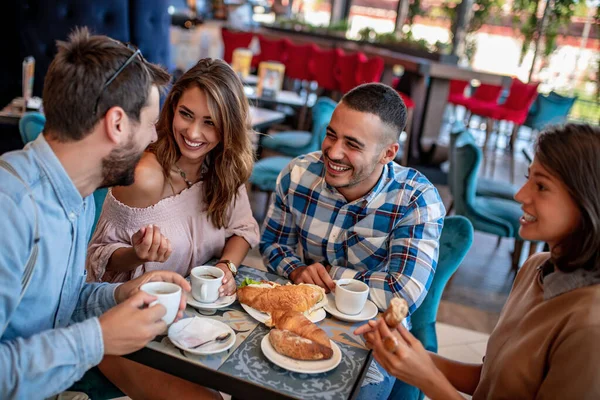 レストランで楽しい時間を過ごしている若い友人 コーヒーショップに座ってコーヒーを飲んでいる若者のグループ — ストック写真